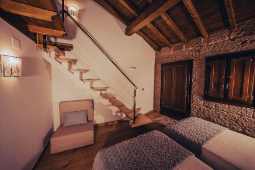 奥伦塞Casa Rural Vilar de Flores的一间卧室设有楼梯、一张床和一把椅子