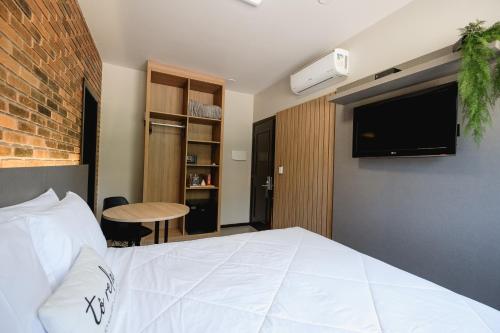 本图贡萨尔维斯Malbec Casa Hotel的卧室配有一张白色大床和电视。