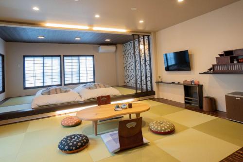 高山英太郎日式旅馆的客房设有两张床、一张桌子和一台电视机。