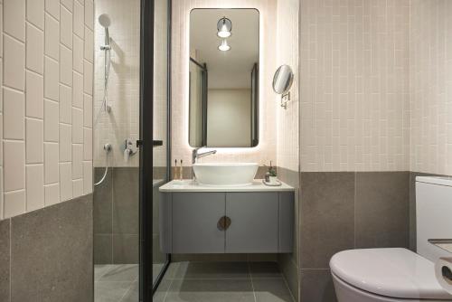 新加坡Citadines Connect Rochester Singapore的一间带水槽、镜子和卫生间的浴室