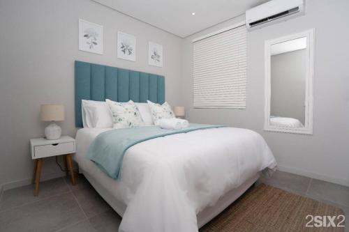 德班Unit 700 @2SIX2 on Florida的一间卧室配有一张白色大床和蓝色床头板