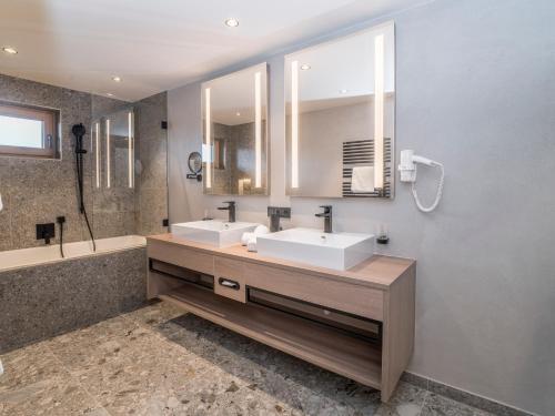 基茨比厄尔Aktiv Hotel Schweizerhof Kitzbühel的一间带两个盥洗盆和大镜子的浴室