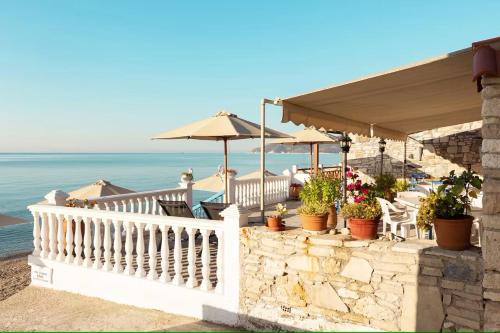 毕达哥利翁Potokaki Beachfront Hotel的一个带椅子和遮阳伞的阳台,享有海景。