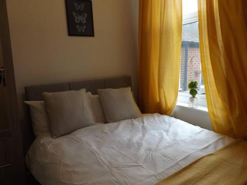 HanleyForest Park House的一张带白色床单和枕头的床,靠窗