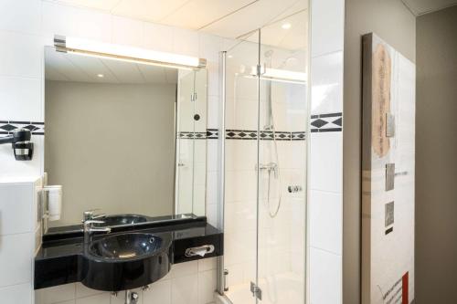 汉诺威elaya hotel hannover city的浴室配有盥洗盆和带镜子的淋浴