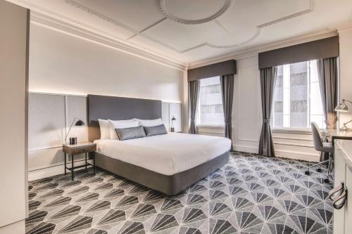 墨尔本The Savoy Hotel on Little Collins Melbourne的酒店客房设有一张床、一张书桌和窗户。