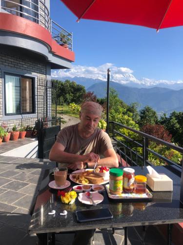 博卡拉Hotel Pristine Himalaya的坐在餐桌上吃一盘食物的人