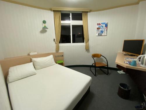 台北Rich Zone Hotel的一间卧室配有一张床和一张带电脑的书桌