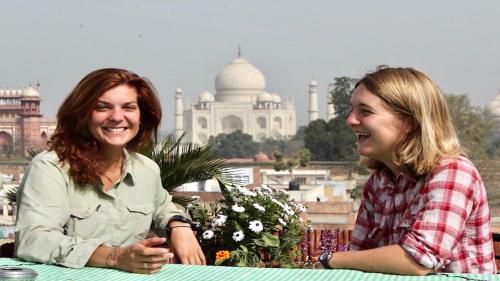 阿格拉Hotel Saniya Palace inn的两名妇女坐在taj mahabalipur前面的桌子上