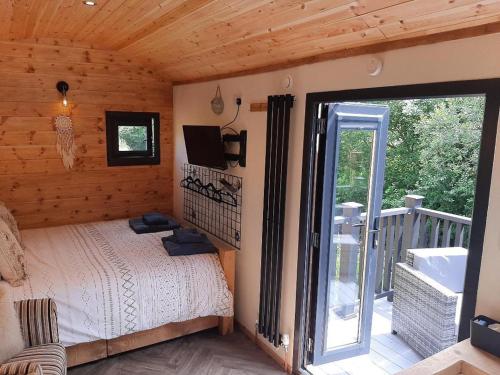 GwalchmaiShepherds Hut with hot tub on Anglesey North Wales的一间卧室设有一张床,阳台配有电视。