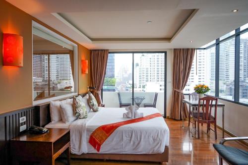 曼谷曼谷美人鱼酒店的一间卧室配有一张床、一张书桌和一个大窗户