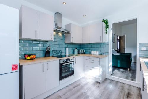 克鲁Spacious 4-bed house in Crewe by 53 Degrees Property, ideal for Business & Contractors - Sleeps 7的厨房配有白色橱柜和蓝色瓷砖