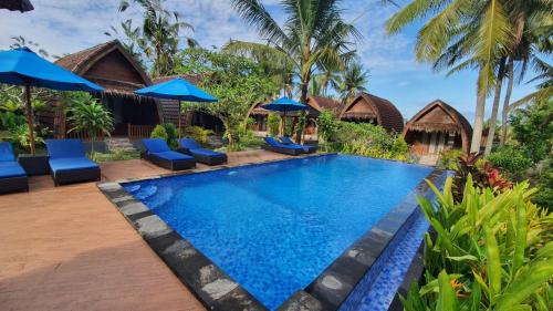 珀尼达岛Kelingking Tatakan Bungalow的度假村的游泳池,配有蓝色的椅子和遮阳伞