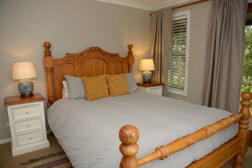 奥兰治博罗戴尔葡萄园度假酒店的一间卧室配有一张木床、两个床头柜和两个灯。