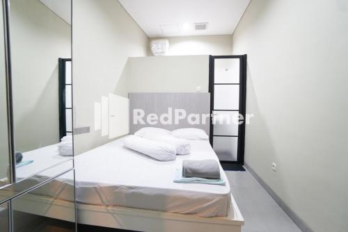 雅加达Tomang Gelong Guest House Syariah Mitra RedDoorz的客房配有带白色床单和枕头的床。