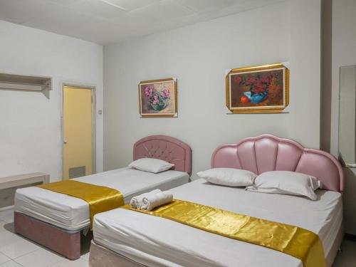 泗水Yellow Sapphire RedPartner near Mayjend Sungkono的两张睡床彼此相邻,位于一个房间里