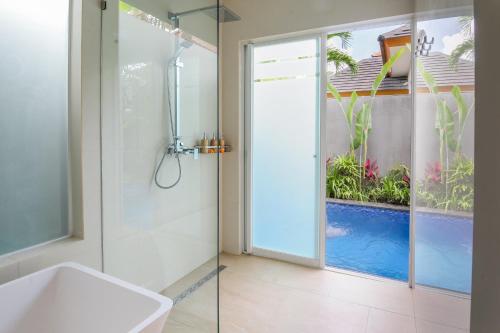 塞米亚克Le Cielo Romantic Villas by Maviba的浴室设有淋浴,透过玻璃门可进入游泳池