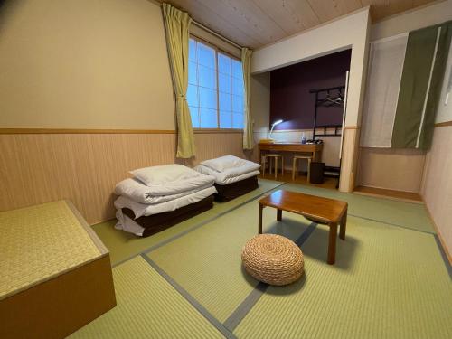富士河口湖GuestHouse OC的客房设有两张床、一张桌子和一扇窗户。