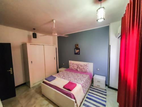 卢克索Sunshine House的一间小卧室,配有床和红色窗帘