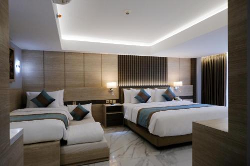 库塔Dream of Aventus Hotel Kuta的酒店客房配有两张床和一张书桌