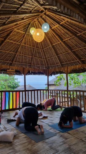 八打雁RUSTIQUE RUE Mabini - Hostel的一群人在草屋下做瑜伽
