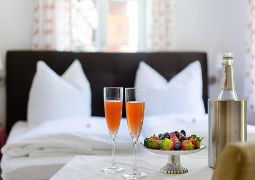 圣吉尔根迈亚湖法酒店的两杯香槟和一碗水果放在桌子上
