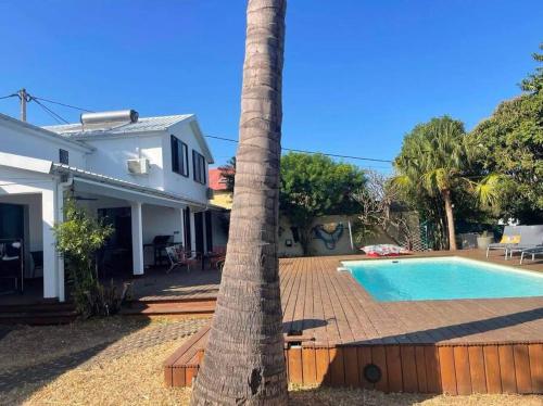 Le Bois de NèflesVilla Jujubes的棕榈树,毗邻带游泳池的房子