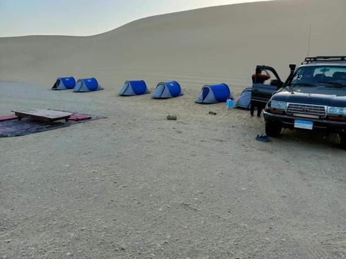 BawatiEscape Camp的一辆停在海滩上的卡车,上面有蓝色的帐篷