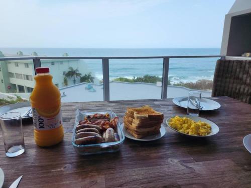 拉姆斯盖特Breathtaking 3 Bedroom unit with amazing sea views的一张桌子,上面放着一盘食物和一瓶橙汁