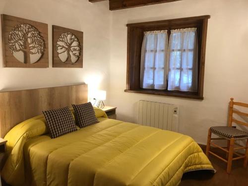 普拉德埃米塔la Caseta Boi Taull - 2 habitaciones的一间卧室配有一张黄色的床、窗户和椅子
