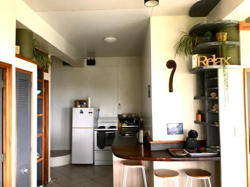 阿希帕拉90 Mile Paradise Ahipara的厨房配有白色冰箱和带凳子的台面