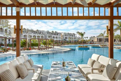 考拉亚湾Steigenberger Resort Alaya Marsa Alam - Red Sea - Adults Friendly 16 Years Plus的度假村的游泳池配有白色的椅子和桌子