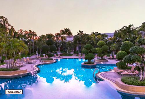 北芭堤雅泰花园度假酒店的棕榈树和椅子的度假村的游泳池