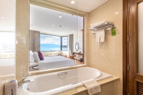 岘港Rosamia Da Nang Hotel的带浴缸的浴室和卧室
