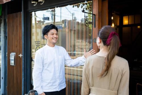 东京Bamba Hotel Tokyo-Private Townhouse-的和商店外的女人说话的男人