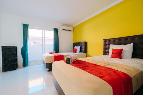 BalianRedDoorz at Kawaii Apartment Jimbaran的一间卧室设有两张床和黄色的墙壁