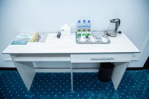 KokandLola Kokand Hotel的白色的办公桌,备有瓶装水和饮料