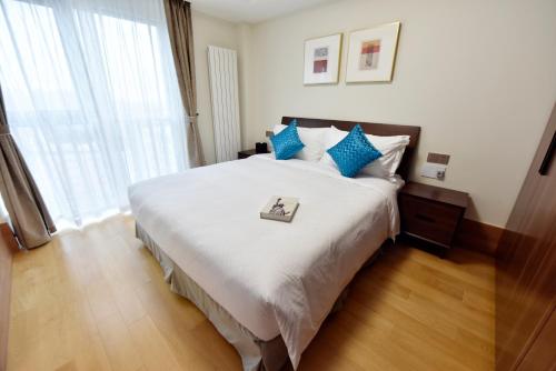 上海上海金桥中环碧云庭服务公寓的卧室配有带蓝色枕头的大型白色床