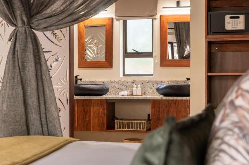 维多利亚瀑布Shongwe Oasis的一间带两个盥洗盆的浴室和一张位于客房内的床。
