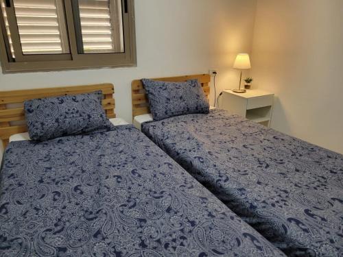 萨法德Home away from home的一间卧室配有两张蓝色床罩和窗户。