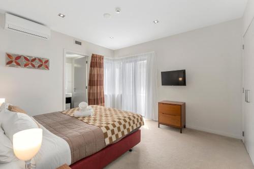 派西亚The Waterfront - Paihia Holiday Apartment的一间卧室配有一张床、梳妆台和电视。