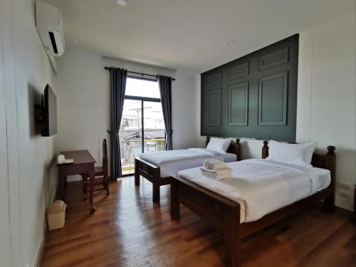 那空拍侬府โรงแรมรชาโขง Racha Khong Hotel的一间卧室设有两张床和窗户。
