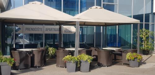 诺维萨德Kristal Garni Hotel的大楼前的一把伞下两把桌子和椅子