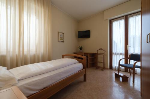 托里德尔贝纳科Casa Vacanza - Casa del Padre Nascimbeni的一间卧室配有一张床、一张书桌和一个窗户。