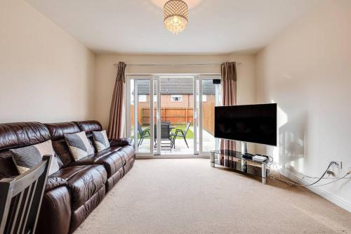 威根Cosy 2 Bedroom Home in Wigan的客厅配有真皮沙发和平面电视