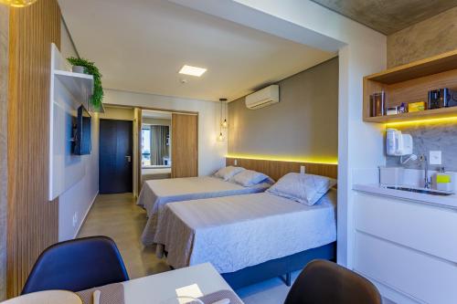 巴西利亚Apart Hotel Centro de Brasília的酒店客房带两张床和一张桌子以及椅子。