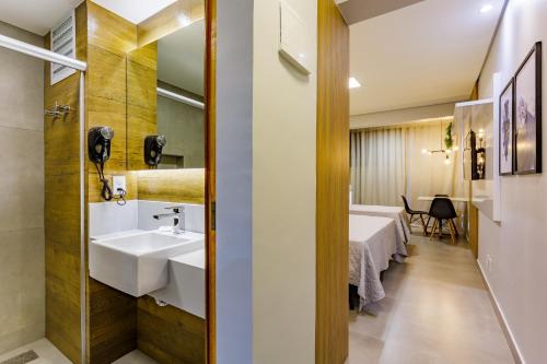 巴西利亚Apart Hotel Centro de Brasília的一间带水槽的浴室和一间带桌子的房间