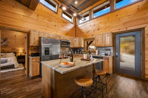 加特林堡The Overlook - '21 Cabin - Gorgeous Unobstructed Views - Fire Pit Table - GameRm - HotTub - Xbox - Lots of Bears的小屋内的厨房设有木制橱柜和一个大岛