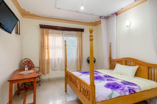 恩德培Airport Side Hotel Entebbe的一间卧室配有一张床、一张桌子和一台电视