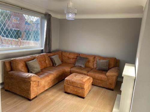 切斯特Ideal Abode Greenfields的客厅里设有一张棕色皮沙发,配有窗户